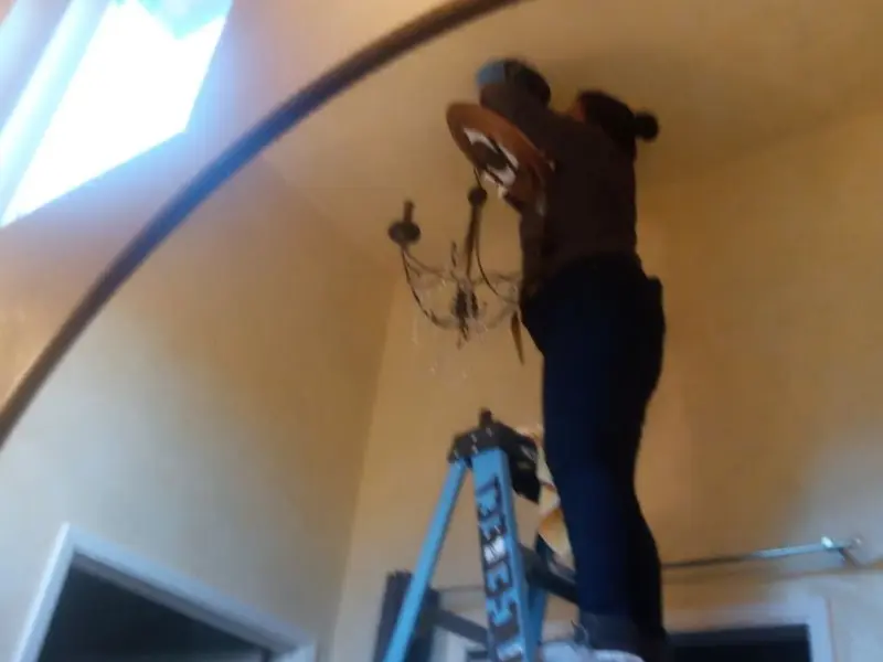 Electrician installing a chandelier in a Dewey residence